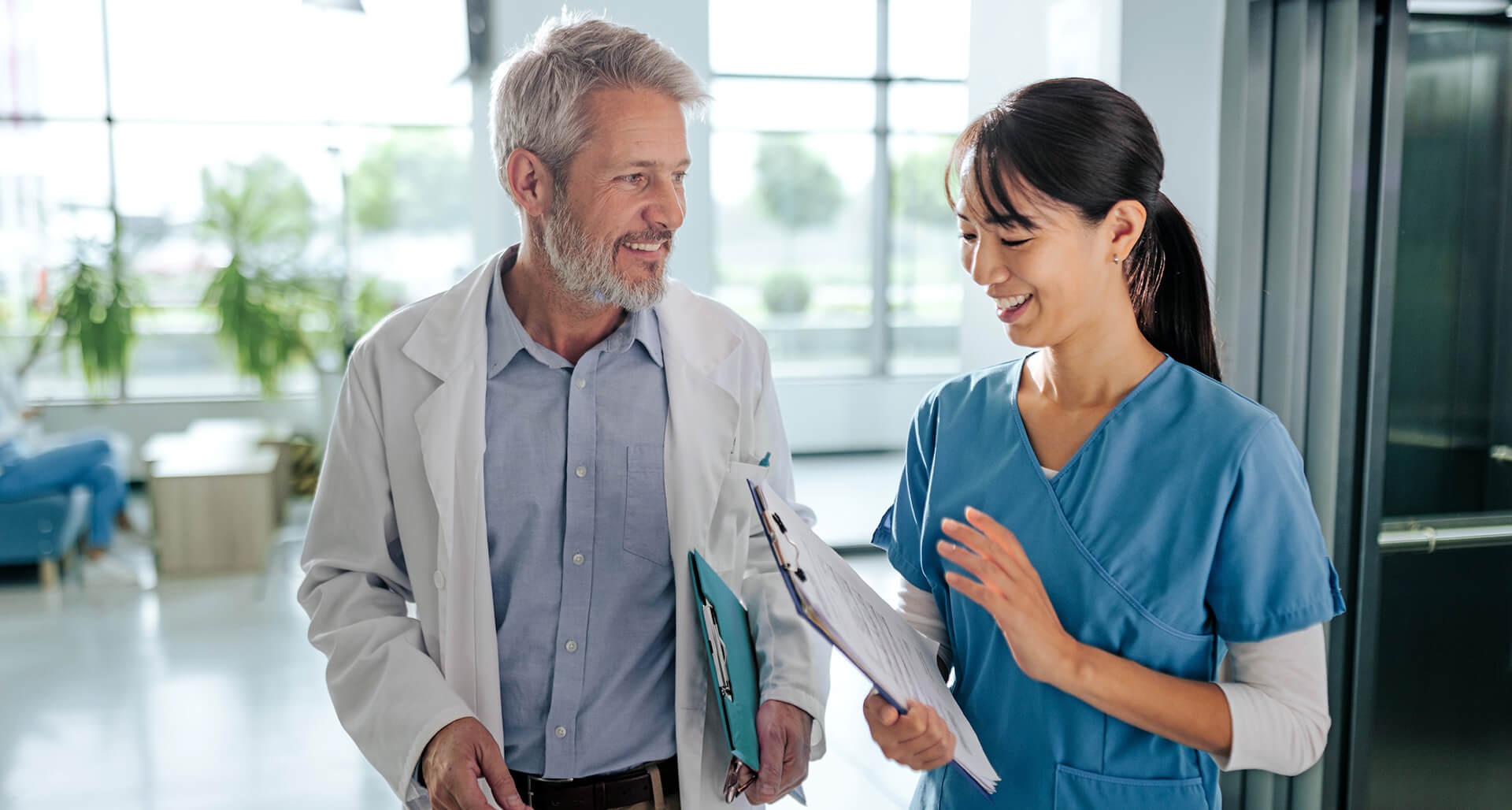 Reifer männlicher Arzt und mittelerwachsener weiblicher Arzt gehen und sprechen