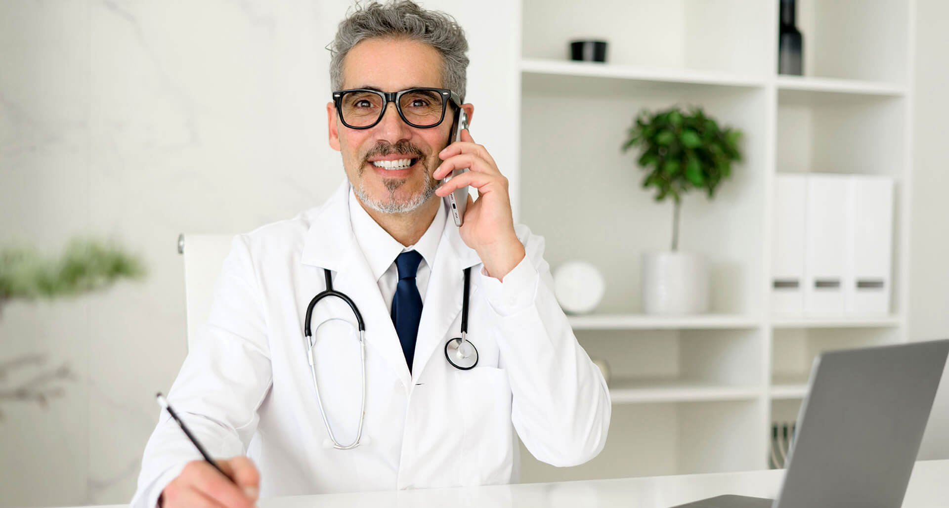 Erfahrener, selbstbewusster Oberarzt mit grauen Haaren beim Telefonat