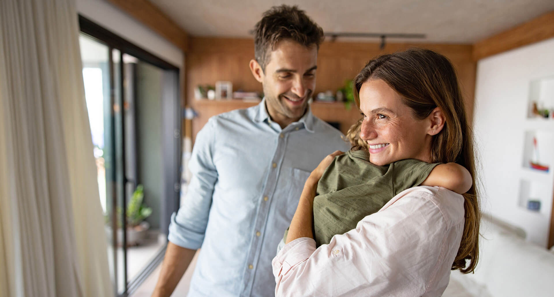 Junges Paar mit kleinem Kind steht im eigenen Haus