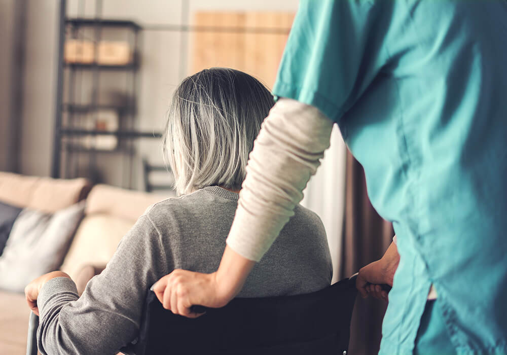 Mitarbeiter des Gesundheitswesens mit älterem Patienten im Rollstuhl