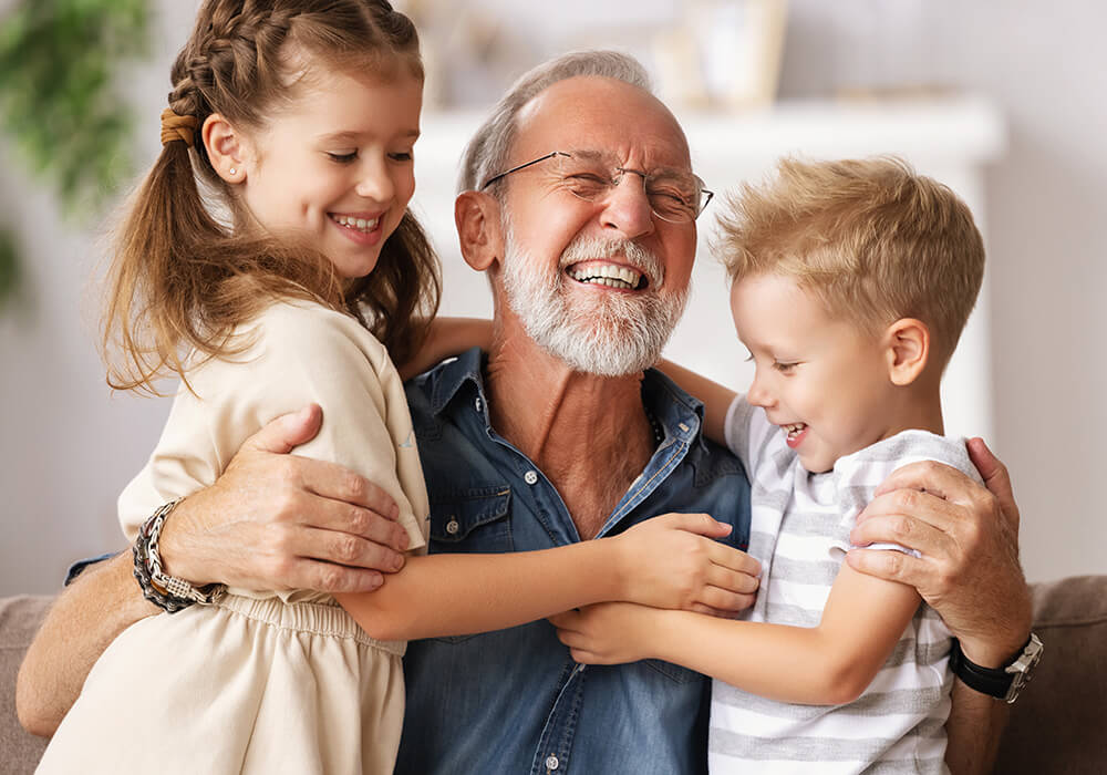 Großvater umarmt Enkelkinder auf Sofa