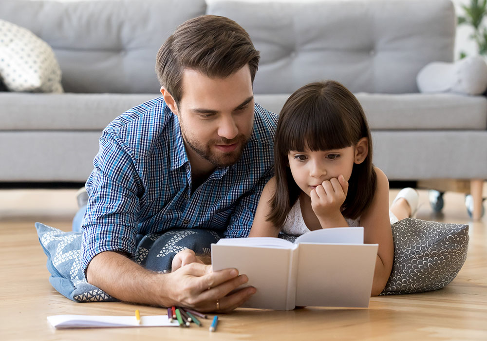 Kleine Tochter und Vater schauen sich ein Buch zusammen an
