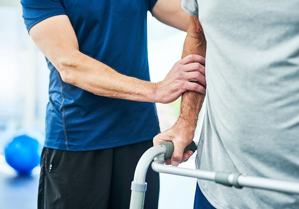 Erste Gehversuche mit Hilfe des Therapeuten