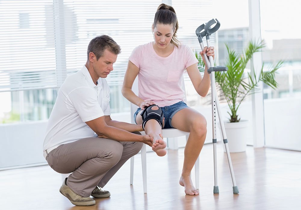 Bei der Reha: Arzt untersucht das Knie seiner Patientin
